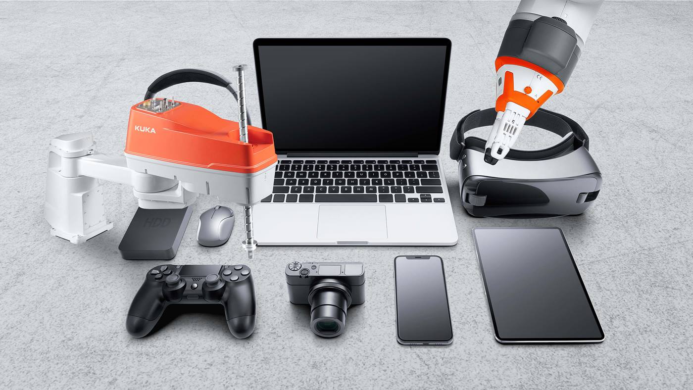 Verschiedene Geräte der Unterhaltungselektronik - Laptop, Smartphonw, Spielkonsole, Tablet, Kopfhörer, externe Festplatte, Maus, VR-Brille - und zwei KUKA Roboter